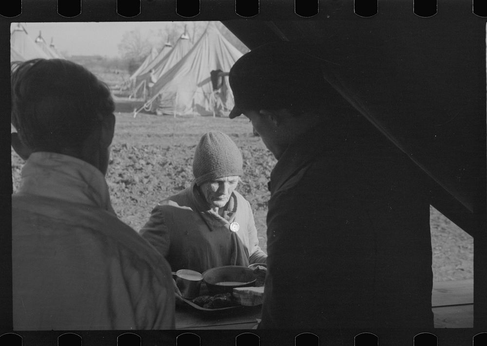 An old lady at mealtime in the camp for white refugees from the flood of 1937, Forrest City, Arkansas. Sourced from the…