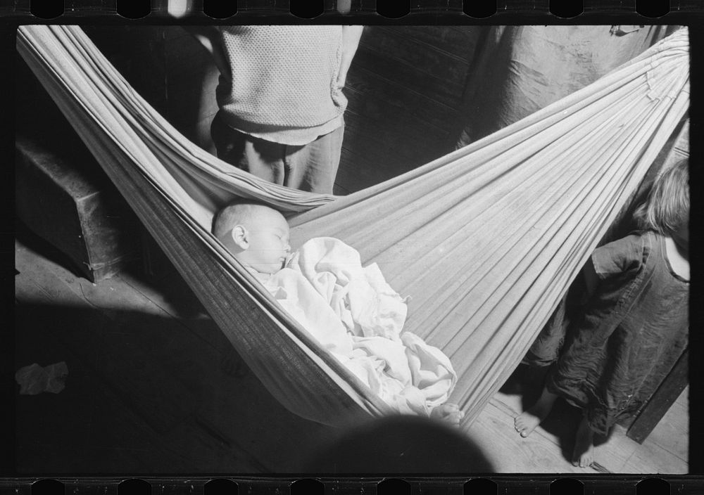 [Untitled photo, possibly related to: Baby asleep in hammock. The hammock saves space in a shack already overcrowded. Puerta…