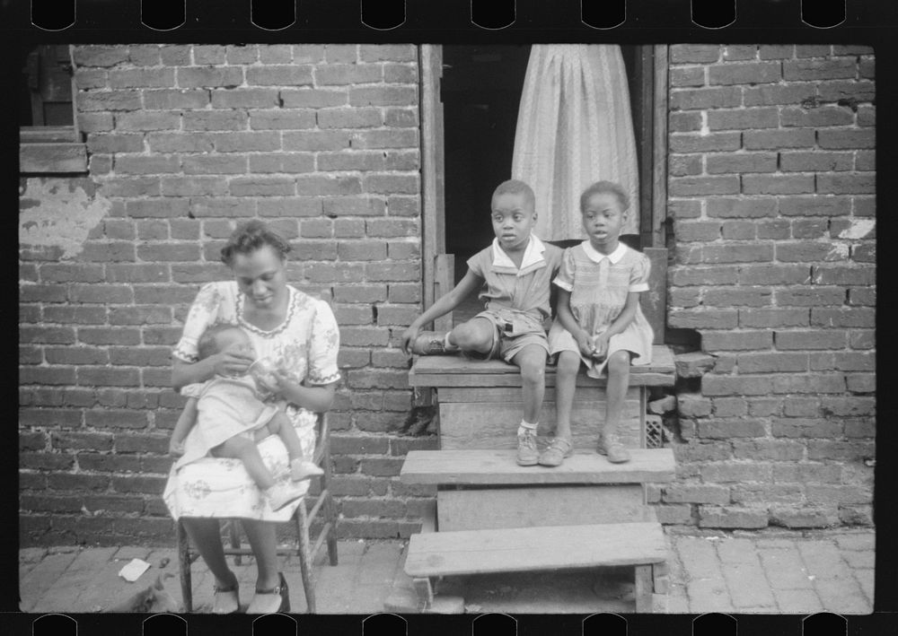 [Untitled photo, possibly related to:  family in front of their alley dwelling. The older woman is a cleaning woman in the…