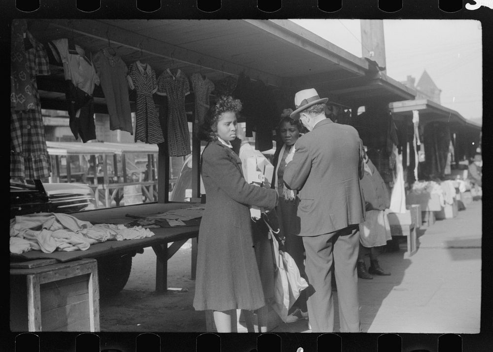 es making purchases from white proprietor of street clothing stall, Black Belt, Chicago, Illinois. Sourced from the Library…