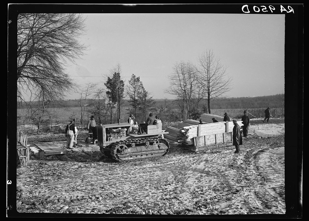 Wooden sleds drawn by tractor bringing supplies from main road to project at Berwyn, Maryland. During the winter months…