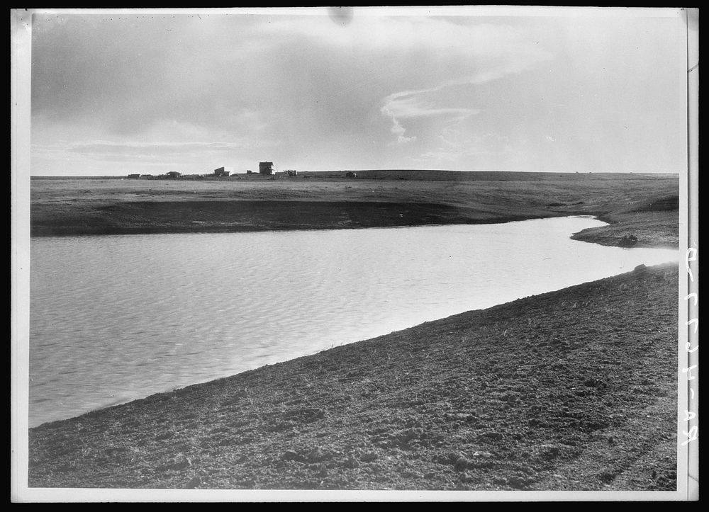Completed stock water dam which will benefit ranch in background. Pennington County, South Dakota. Sourced from the Library…