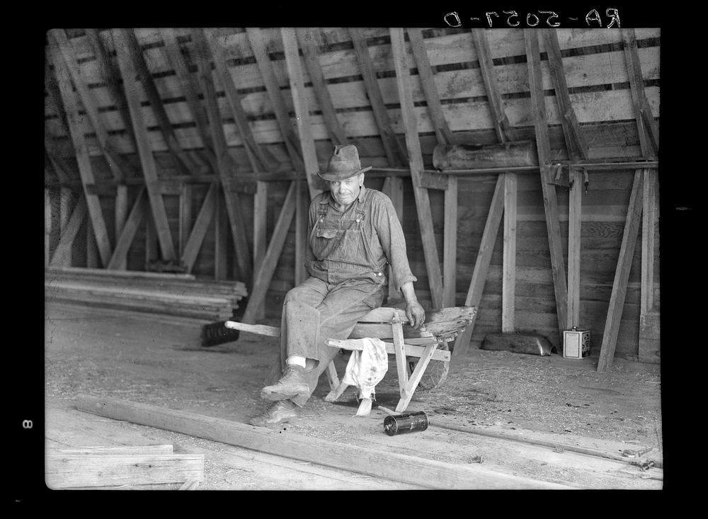 Farmer near Beach, North Dakota, sitting in his empty barn. Sourced from the Library of Congress.