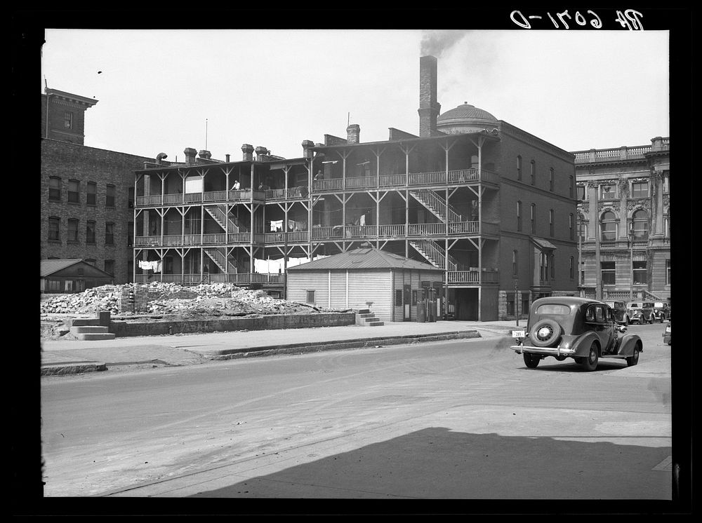 Rear of apartments at 8th and Wisconsin, with Milwaukee Public Library in background. Milwaukee, Wisconsin. Sourced from the…