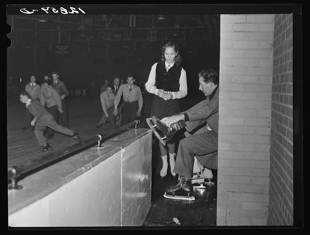 Chevy Chase Ice Palace, Washington. D.C. Skater fastening on skates while companion watches. Sourced from the Library of…