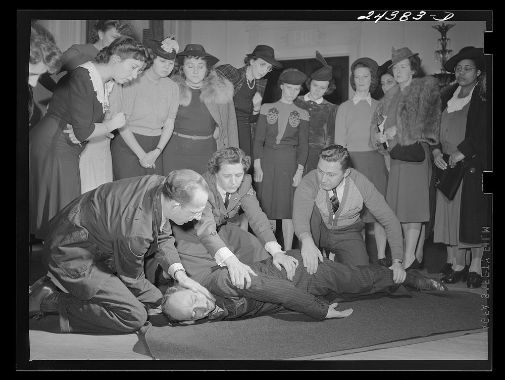 Civilian defense volunteers receiving instruction in proper care for man with spine injury. The first aid class of the…