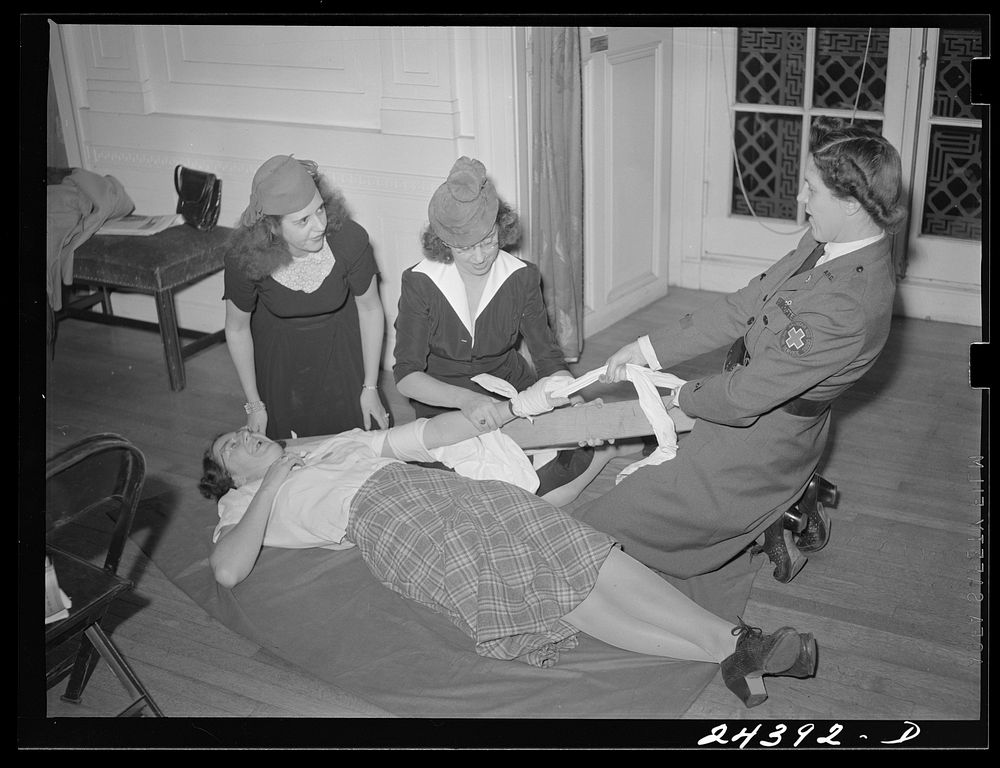 Civilian Defense volunteers receiving instruction in treatment of fractured arm. First aid class. American Red Cross, New…