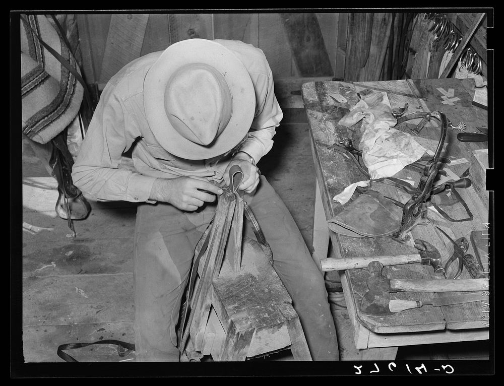 Cowhand working with leather in saddle room. Quarter Circle 'U' Ranch, Montana. Sourced from the Library of Congress.