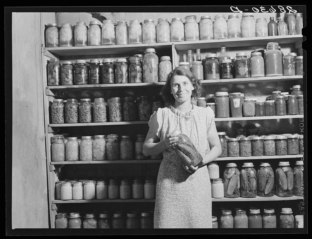 Mrs. H.H. Poland, wife of rehabilitation client, with preserved food. Mesa County, Colorado. Sourced from the Library of…