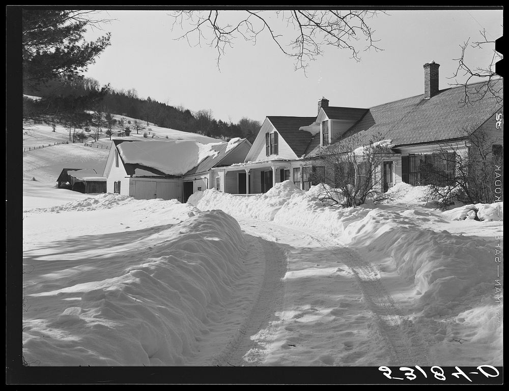 Snow slides off the roof and piles high in front of window of farmhouses. Woodstock, Vermont. Sourced from the Library of…