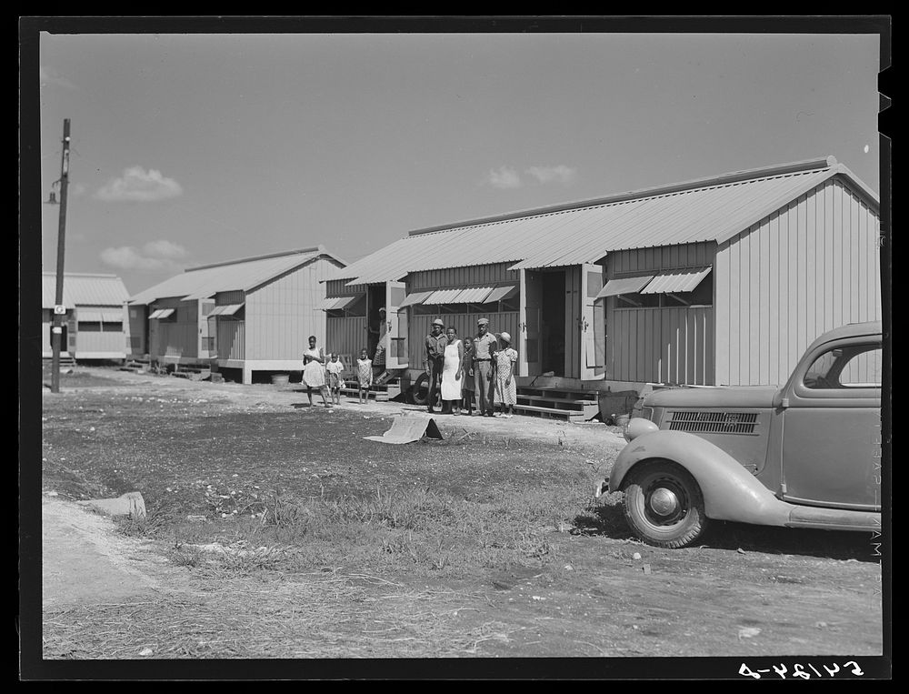 Camp members outside their shelter unit at Okeechobee migratory labor camp. Belle Glade, Florida. Sourced from the Library…