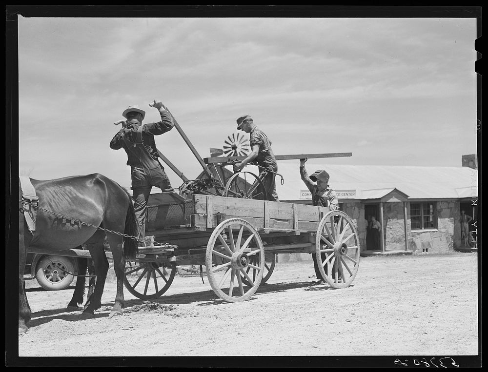 Loading farm machinery onto wagon after repairing at community service center. Faulkner County, Centerville, Arkansas (see…