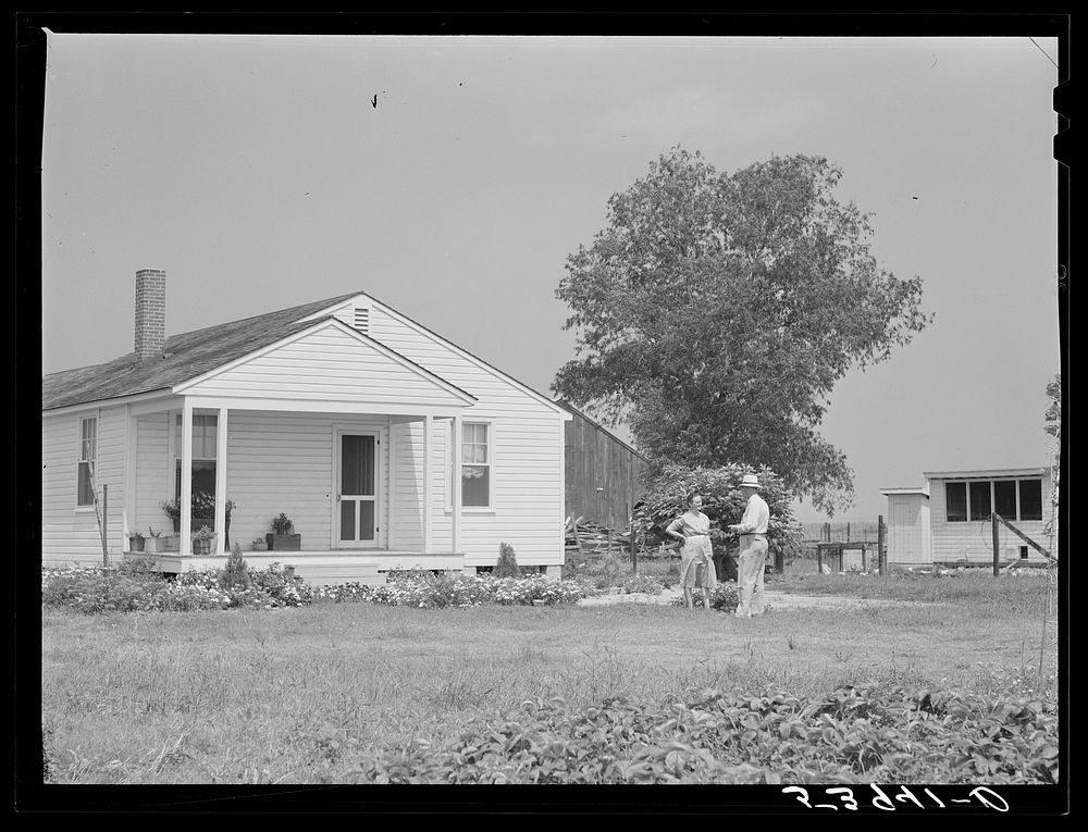 Project manager Mr. B.A. Brady talking to Mrs. J.G. Stanley, one of project families, in front of her home. Transylvania…