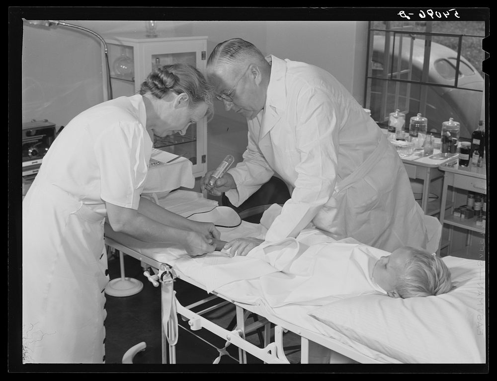 Dr. William J. Buck and nurse Anne Smock dressing infection on child's foot in clinic at Osceola migratory labor camp. Belle…