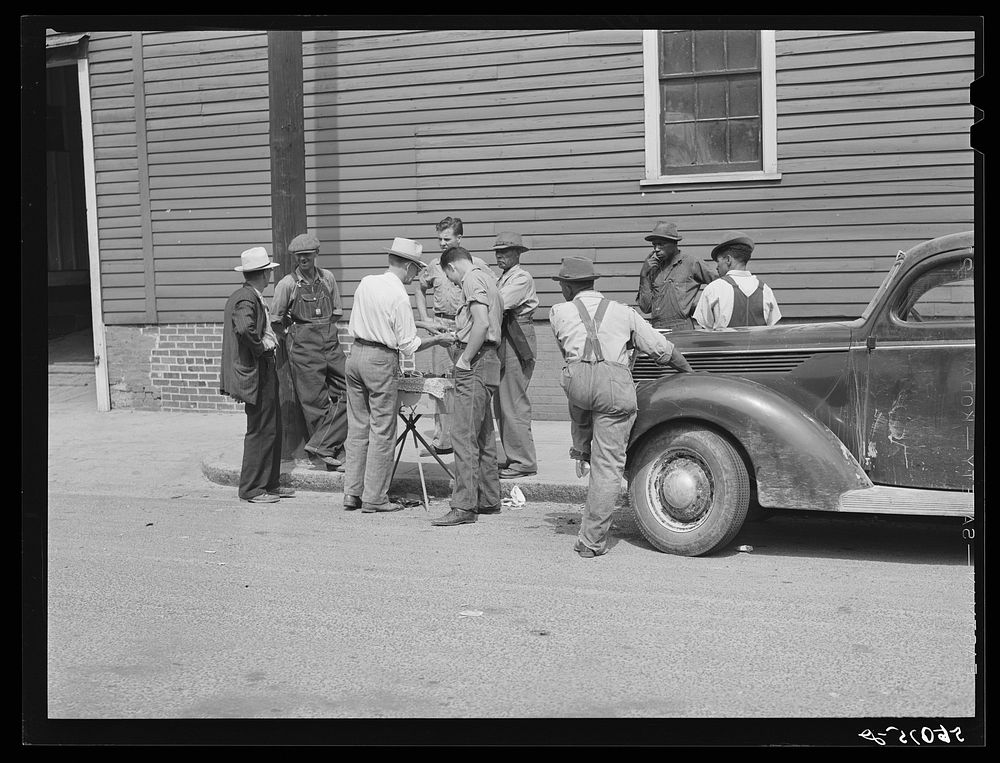 Peddler selling patent medicines to farmers outside warehouse on opening day of tobacco market in Mebane, North Carolina…