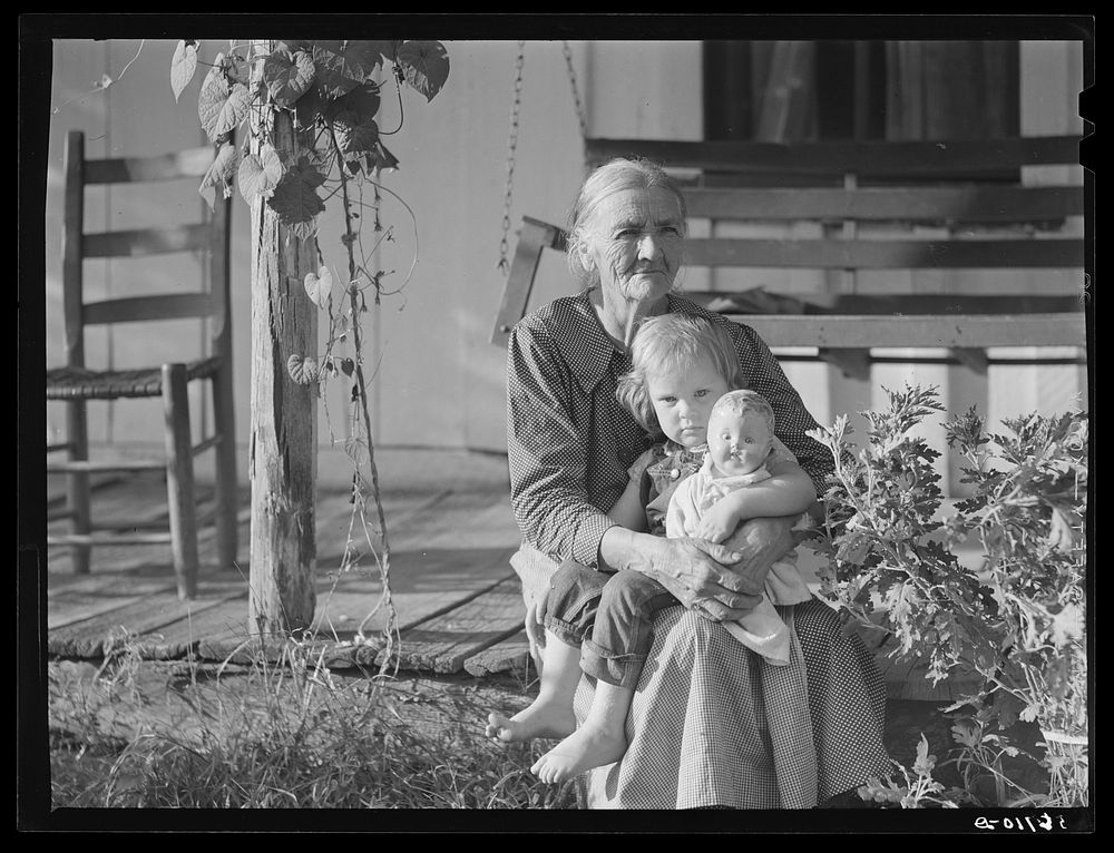 Mountain woman and grandchild sitting on the porch of their home up Frozen Creek, Breathitt County, Kentucky. Sourced from…