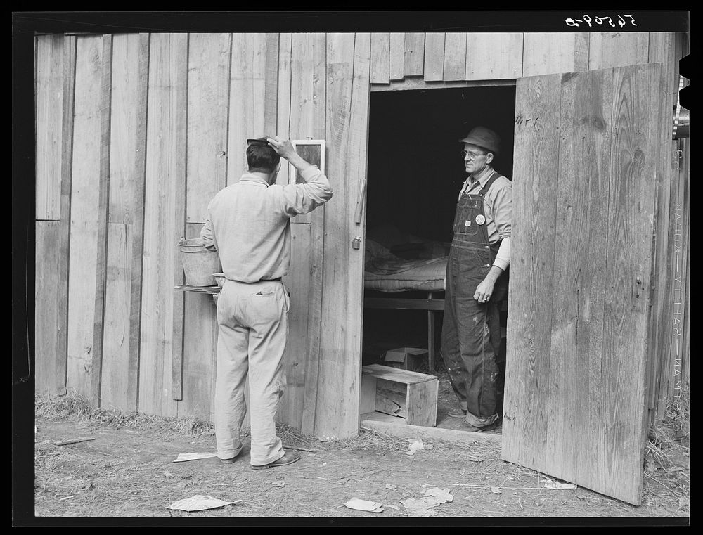 [Untitled photo, possibly related to: Construction workers from Monroe, Louisiana, washing in front of their shack. Water…