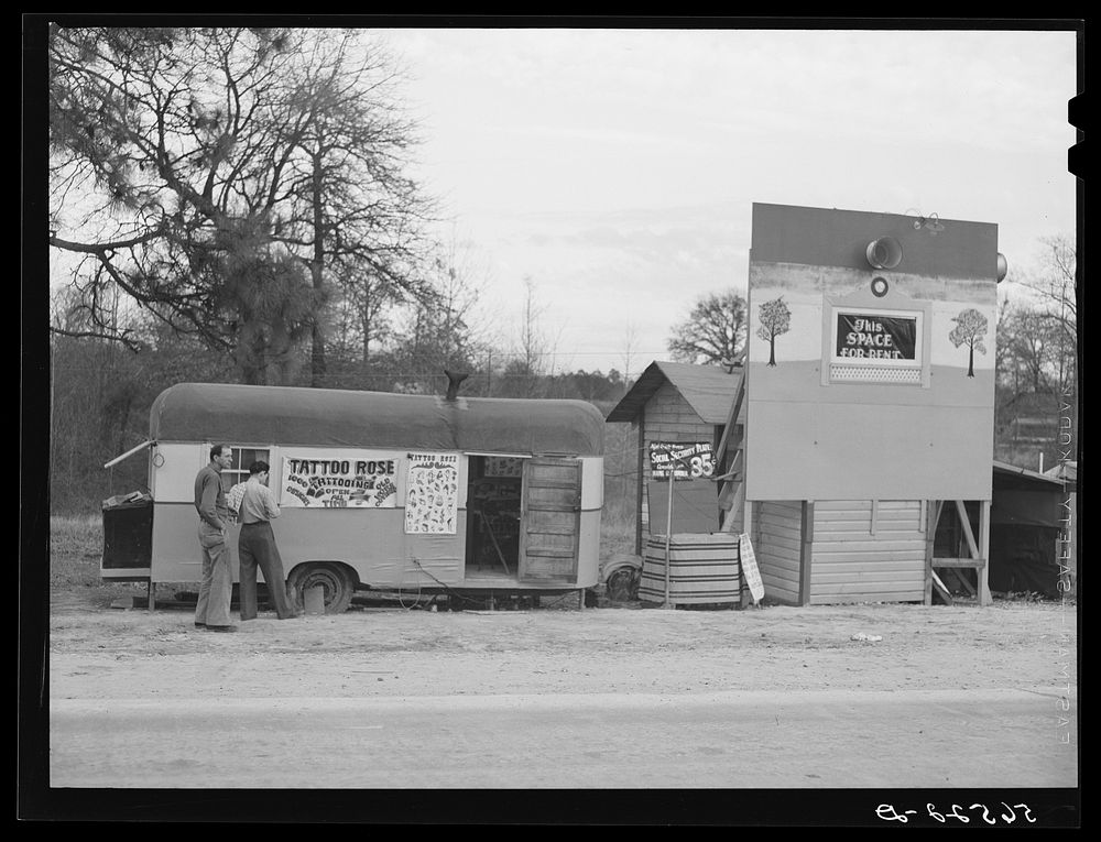 [Untitled photo, possibly related to: Signs and trailer with tattoo artist on highway near Fort Beauregard. Alexandria…