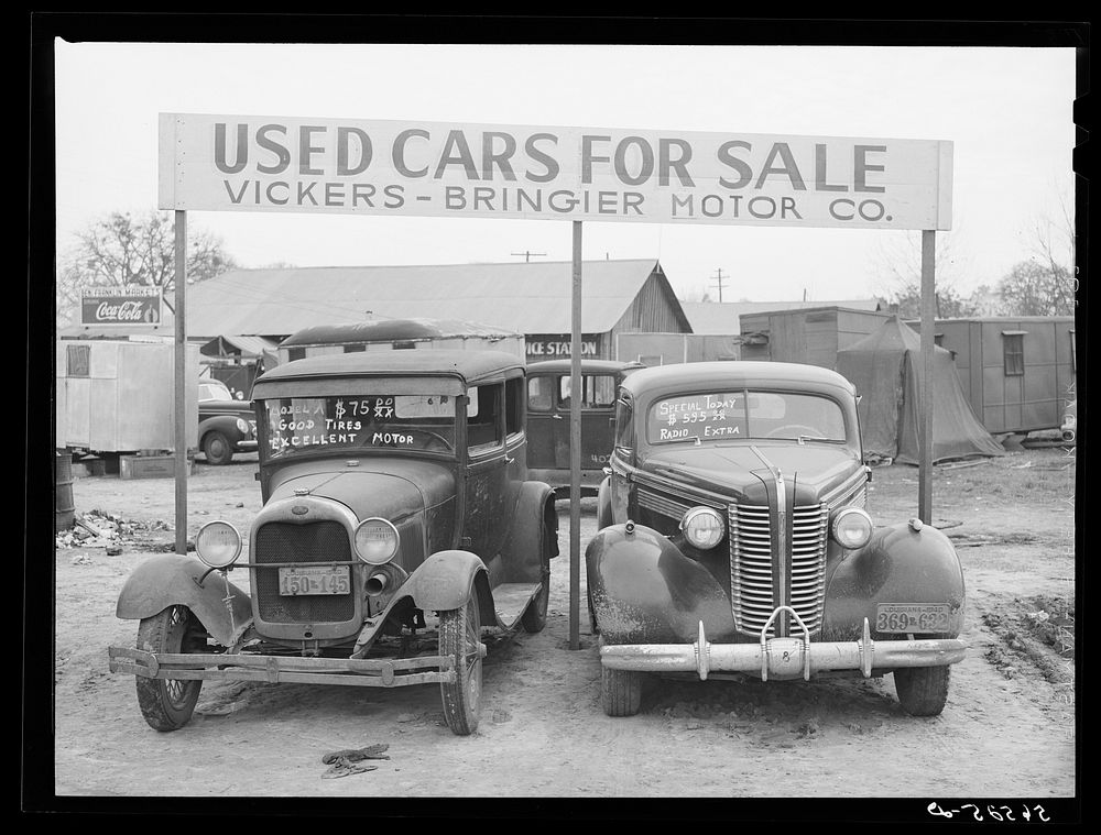 [Untitled photo, possibly related to: Used cars for sale with signs and prices at service station on main highway near…