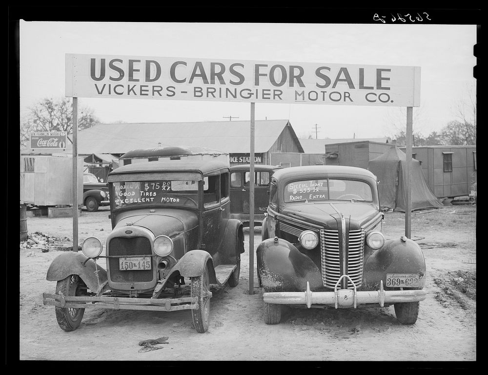 Used cars for sale with signs and prices at service station on main highway near Alexandria, Louisiana. Sourced from the…
