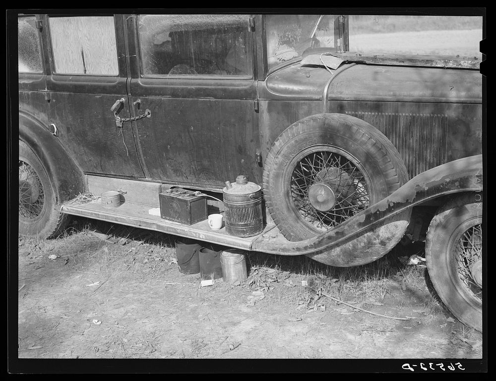Close-up of car from Mississippi used for sleeping as well as shelter and traveling. Evidences of cooking outside are beside…