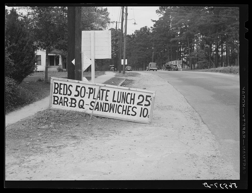 Sign on highway from Fort Beauregard to Alexandria,in Pineville, Louisiana. Beds, fifty cents, plate lunches and barbecue.…