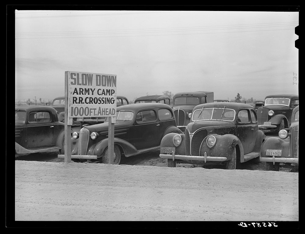 [Untitled photo, possibly related to: Cars of construction workers parked along highway by entrance to Camp Claiborne. Near…