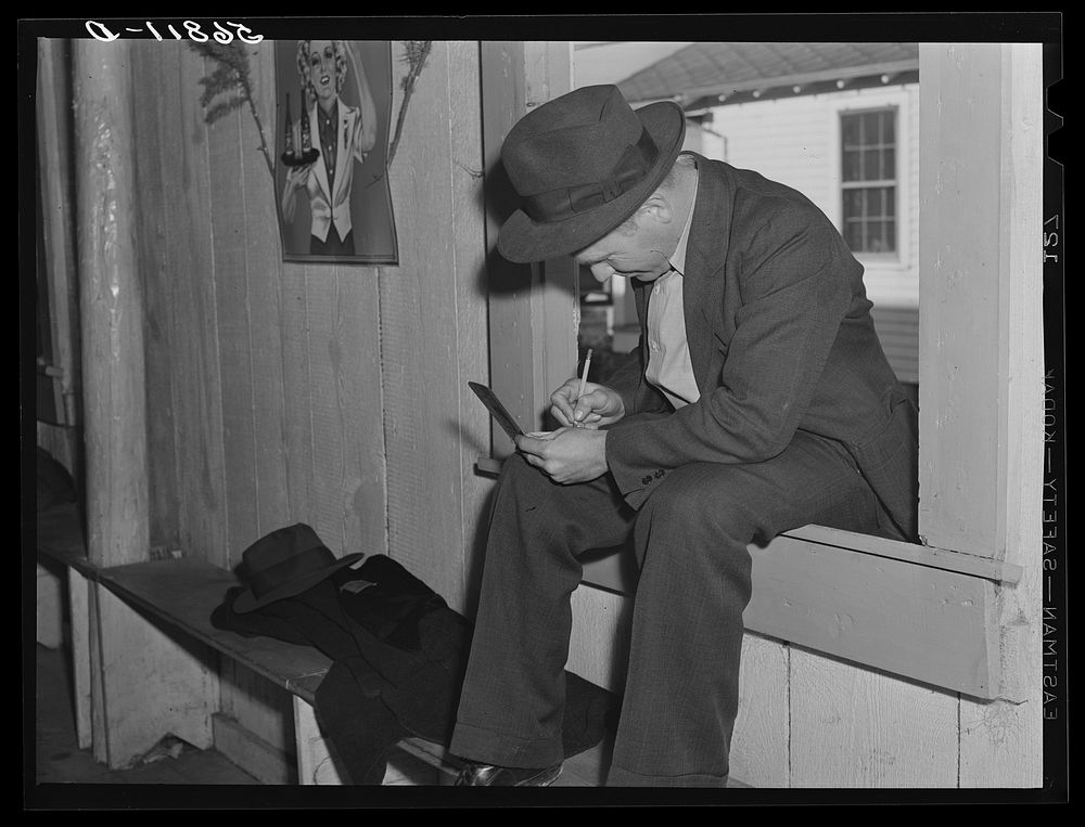 Fur buyer figuring out his bid on the next lot of muskrat pelts. The auction sale is held in a dance hall on Delacroix…