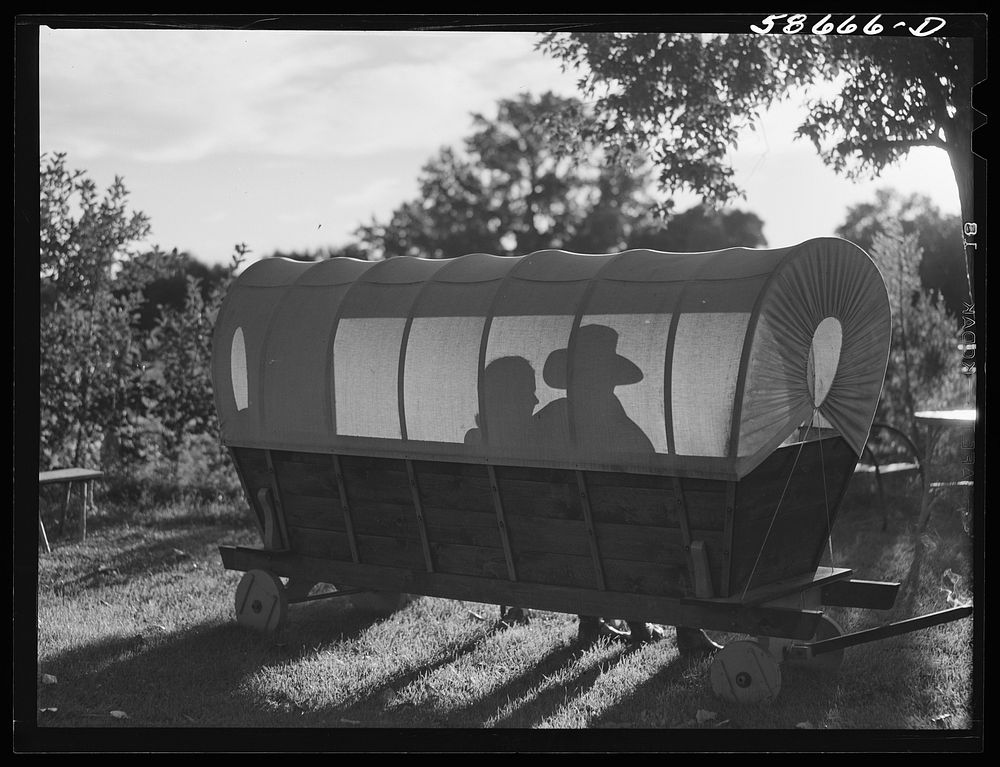 Dudes in a covered wagon garden seat at Quarter Circle U, Brewster-Arnold Ranch Company. Birney, Montana. Sourced from the…