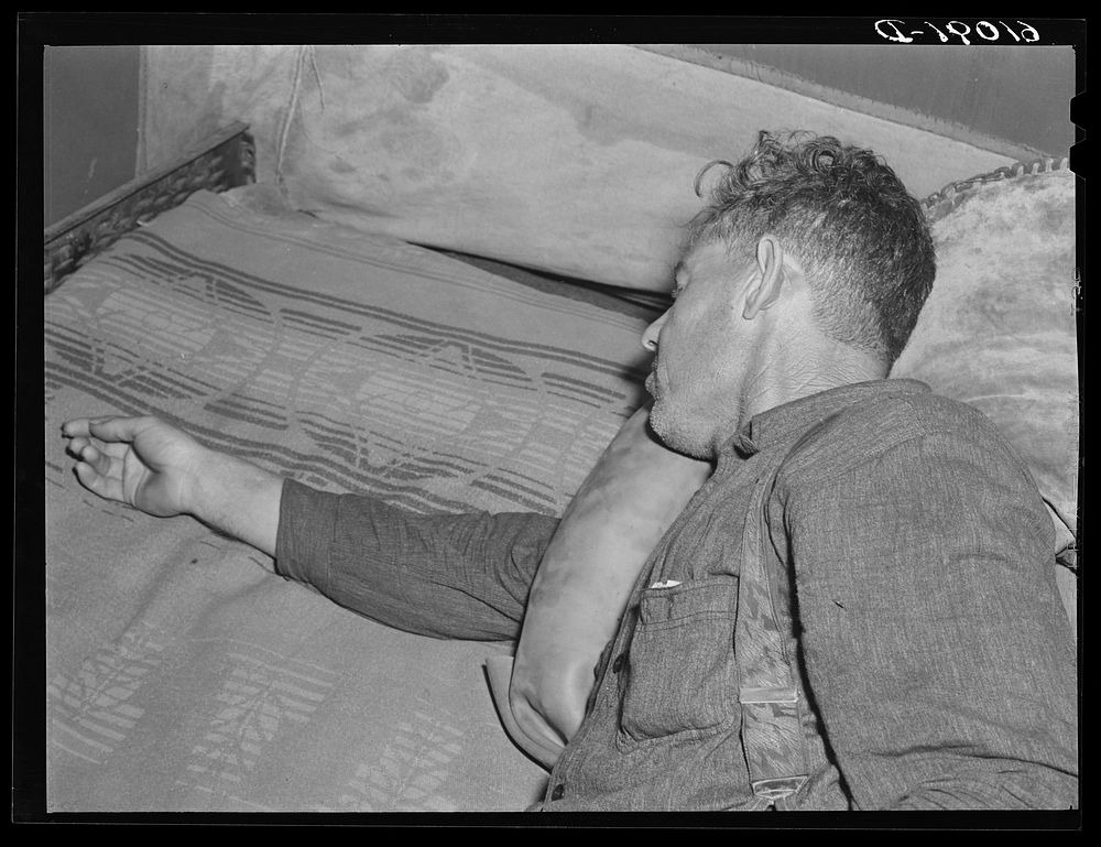 Migrant fruit worker. He has a toothache, and is using an ice-pack made of old inner-tube. Berrien County, Michigan. Sourced…