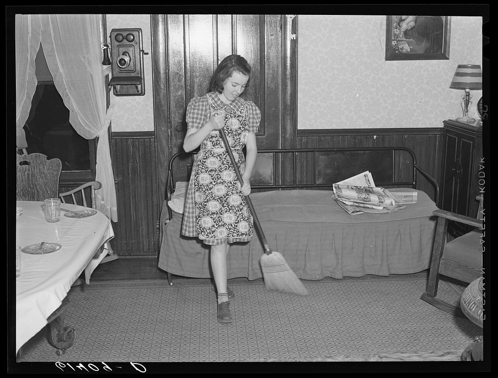 Farm girl sweeping the floor. Meeker County, Minnesota. Sourced from the Library of Congress.