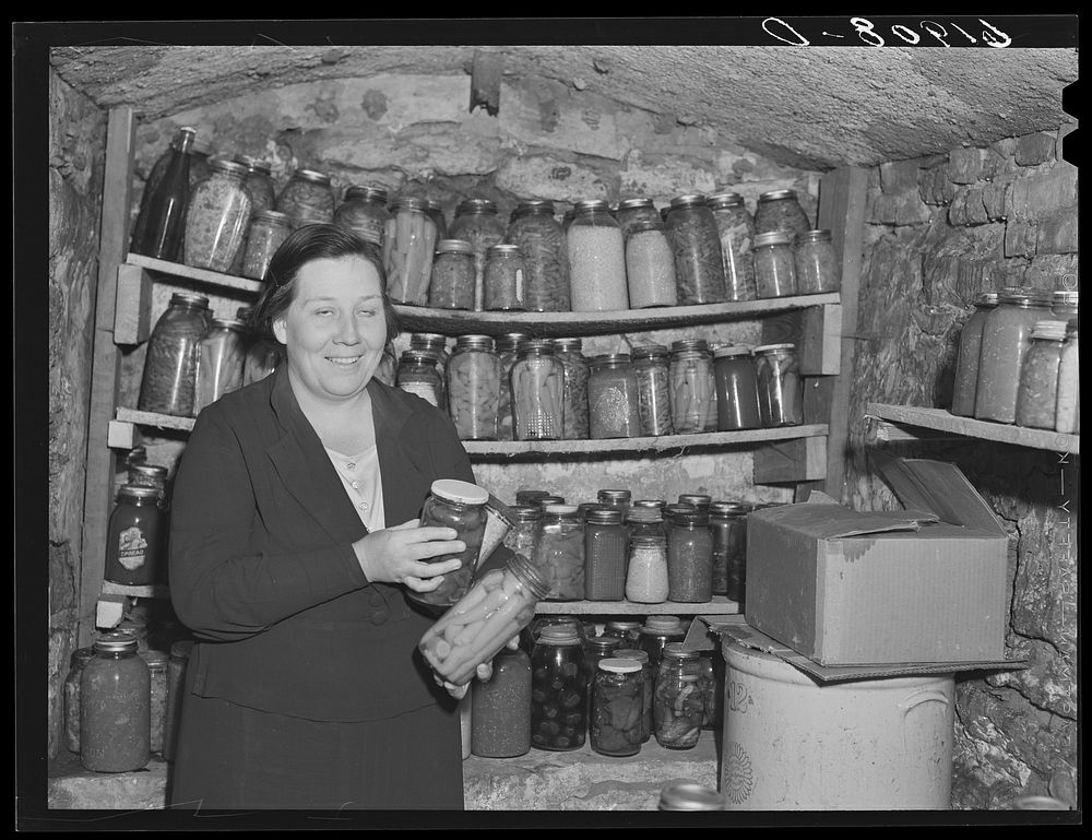 [Untitled photo, possibly related to: Home supervisor examining canned goods of rehabilitation borrower in food storage…