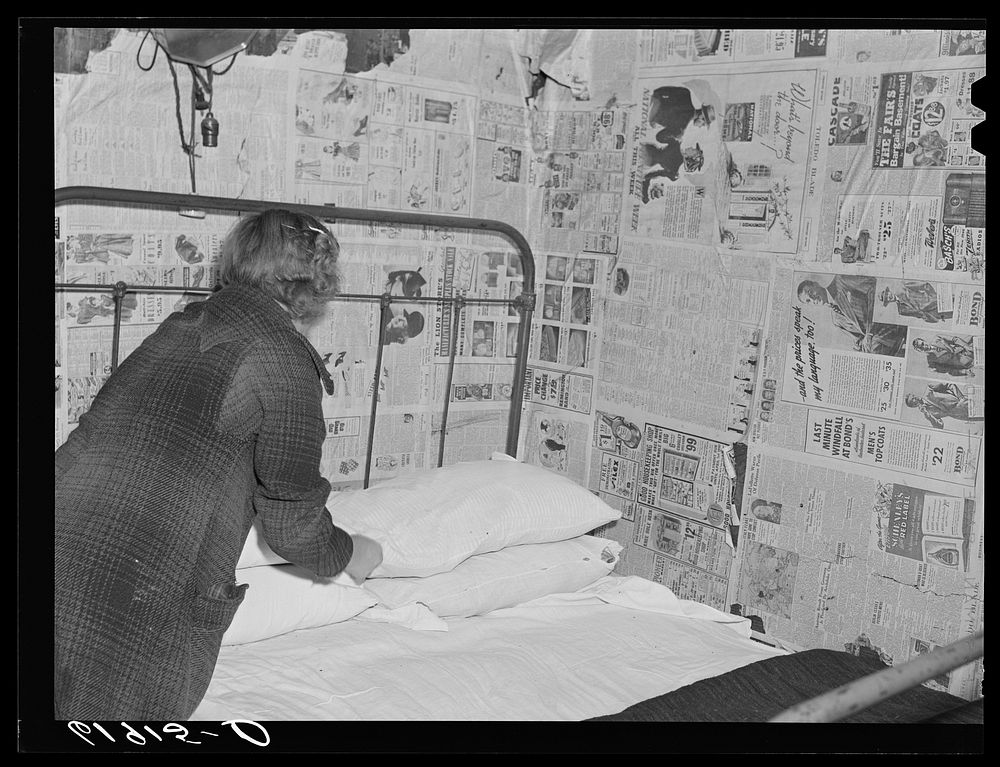 Daughter of day laborer making bed. Family of six sleeps in this one room, two beds. Scioto Marshes, Hardin County, Ohio.…