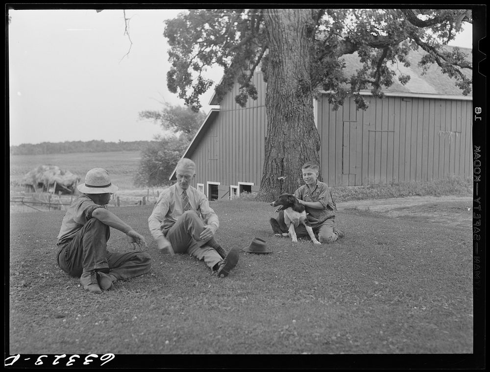 County supervisor talking with FSA (Farm Security Administration) tenant purchase borrower on front lawn of farm he has…