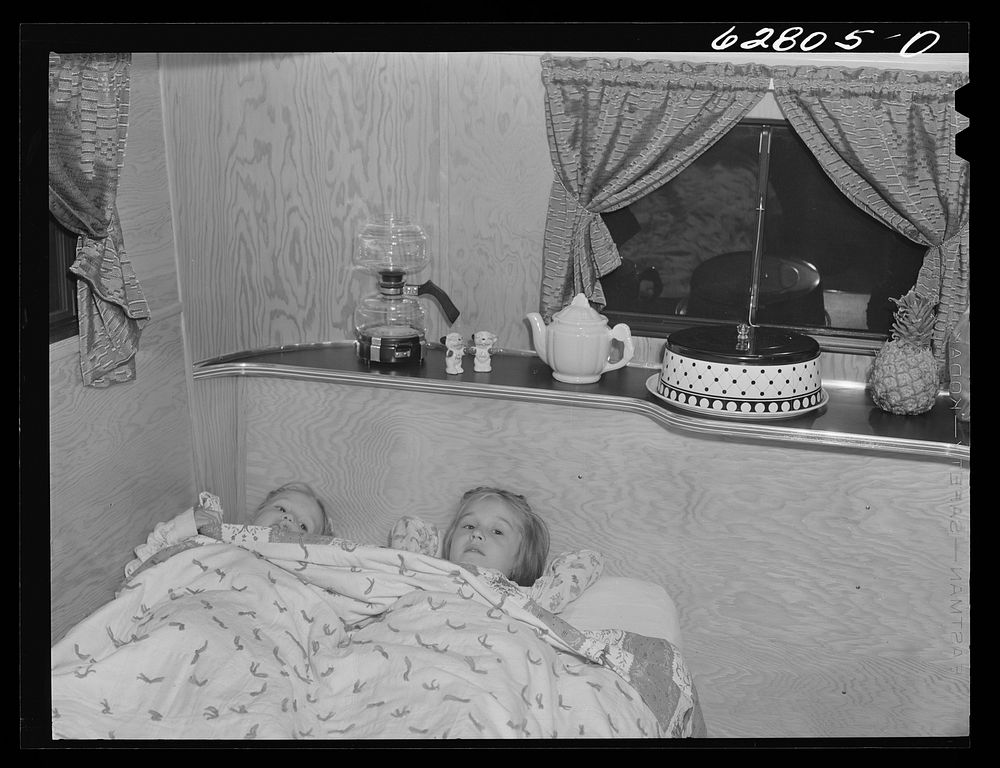 [Untitled photo, possibly related to: Mrs. Jack Cutter putting children to bed. The dining room of the trailer is converted…
