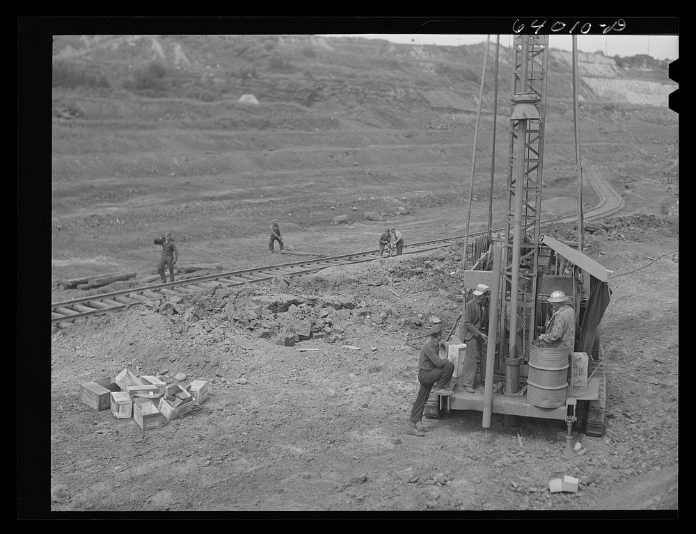 Vertial drill boring hole for blasting crew. Mahoning pit, Hibbing, Minnesota. Sourced from the Library of Congress.