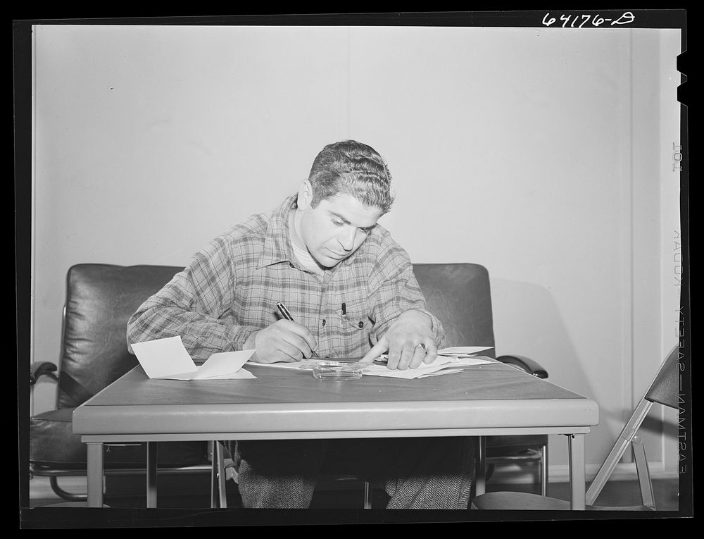 Defense worker writing a letter home in lobby of one of the FSA (Farm Security Administration) dormitories for defense…