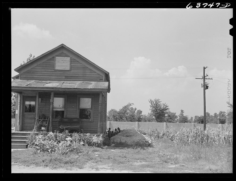 House in  section, Detroit, Michigan. Concrete wall in background is one half mile long, and serves to separate Negro…