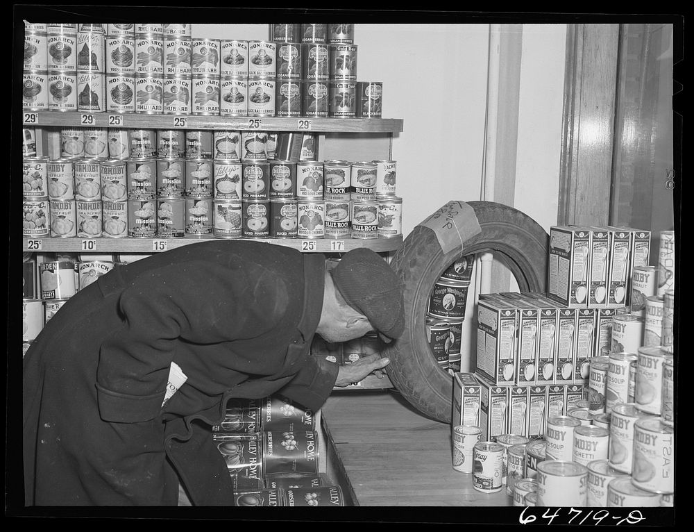 Williston, North Dakota. Inspecting used tire for sale (eight dollars and fifty cents) in grocery store. Sourced from the…