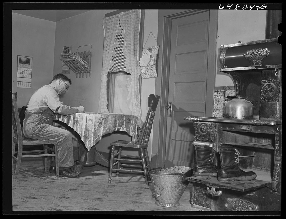 Adams County, North Dakota. North Dakota stock farmer, George P. Moeller, writing a letter at the kitchen table. Sourced…