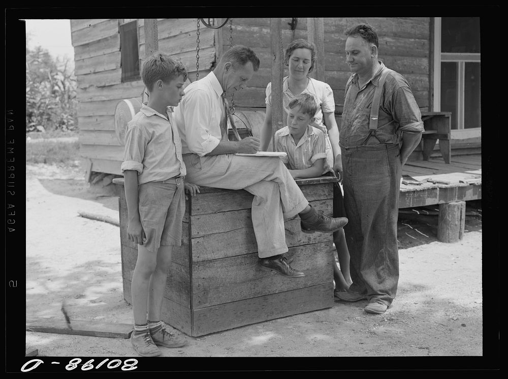 County supervisor talking over home plan with the Hardesty family resting on removed well top. Charles County, Maryland.…
