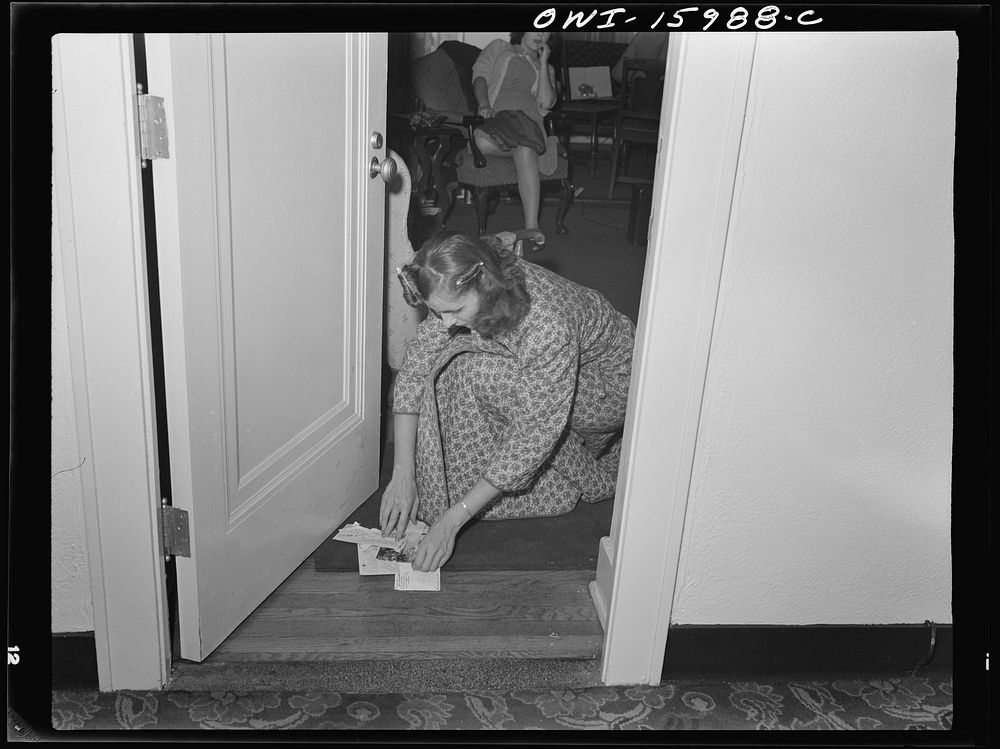 Detroit, Michigan. Girl picking up mail placed under door. Sourced from the Library of Congress.
