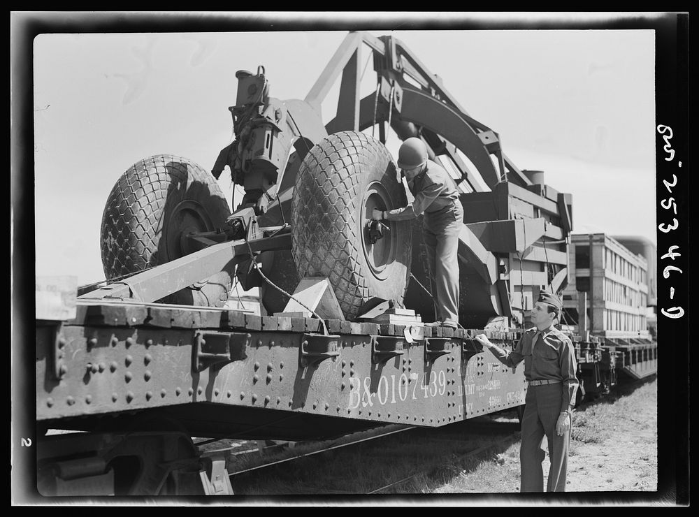 Holabird ordnance depot, Baltimore, Maryland. An officer checking the air pressure of the giant tires on LeTourneau road…