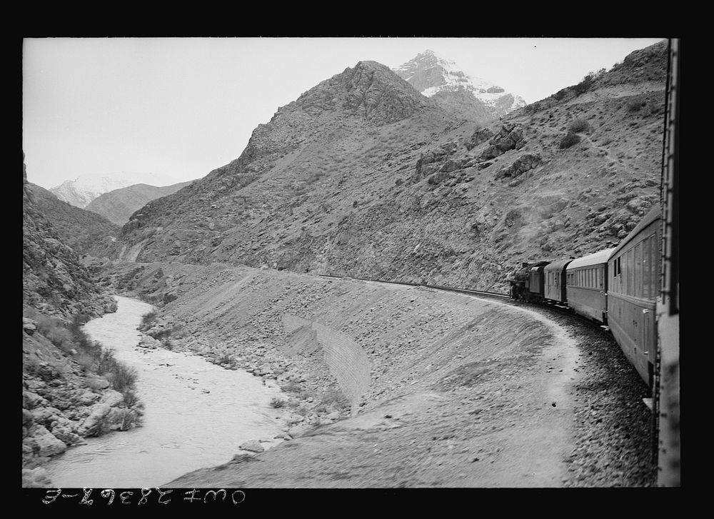 Mountainous route of trains carrying supplies to Russia. An American engine with an American crew is going along a gorge…