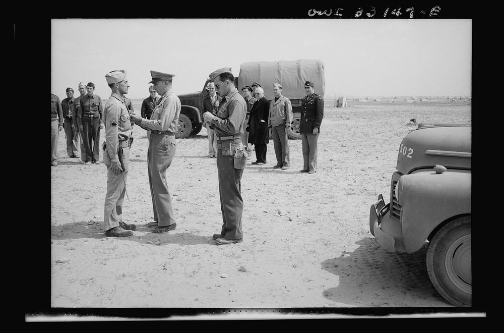 An American sergeant receiving a decoration during the North African campaign. Archbishop Spellman of New York is watching…