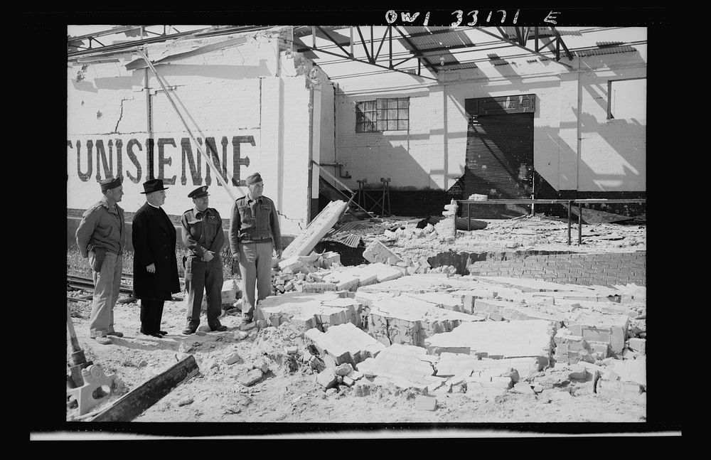 Sfax, Tunisia. Archbishop Francis H. Spellman of New York, viewing bomb damage to the city only recently evacuated by the…