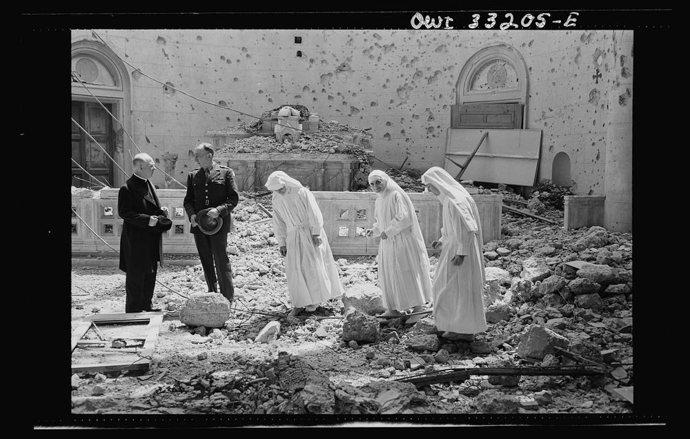 Tripoli, Libya. Archbishop Spellman of New York (left) surveys the ruins of the chapel of the Franciscan Missionaries of…