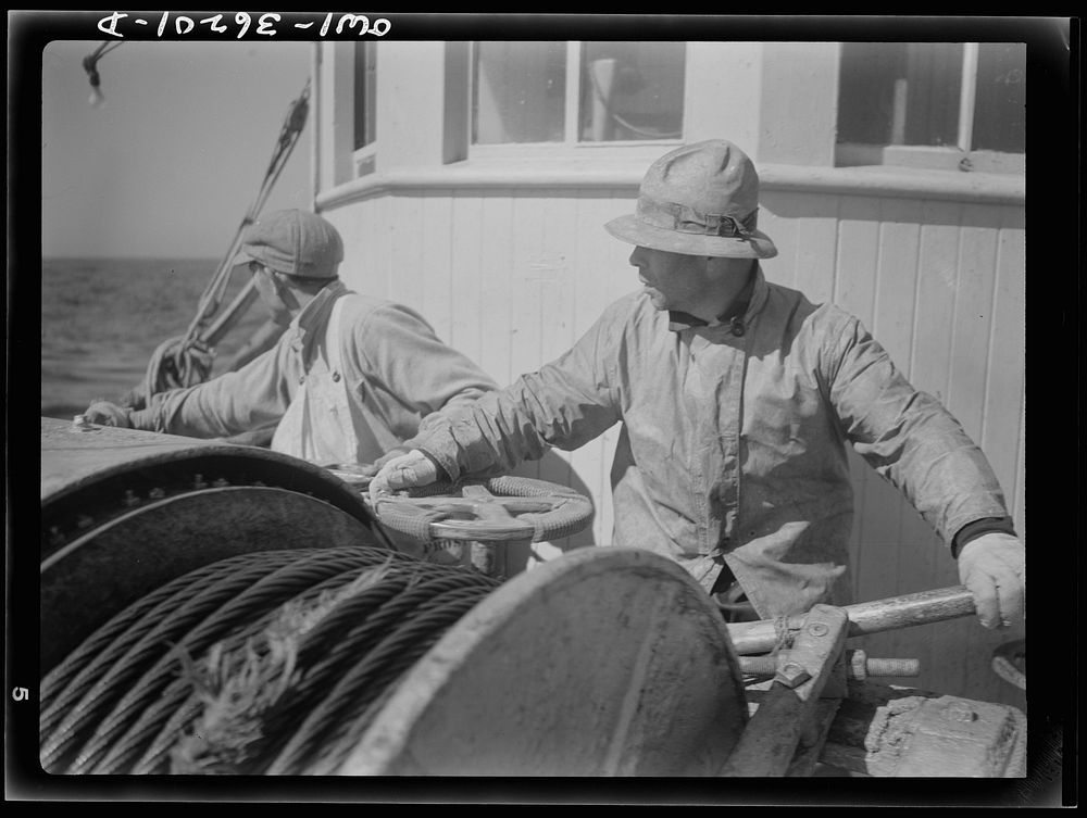 On board a fishing vessel out from Gloucester, Massachusetts. Winch control men intent on seeing to it that the proper…