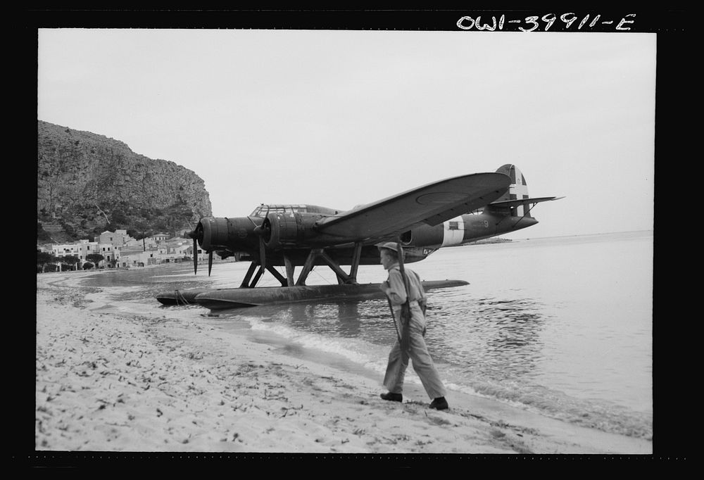 An Italian seaplane on the Sicilian beach guarded by a British soldier. Sourced from the Library of Congress.