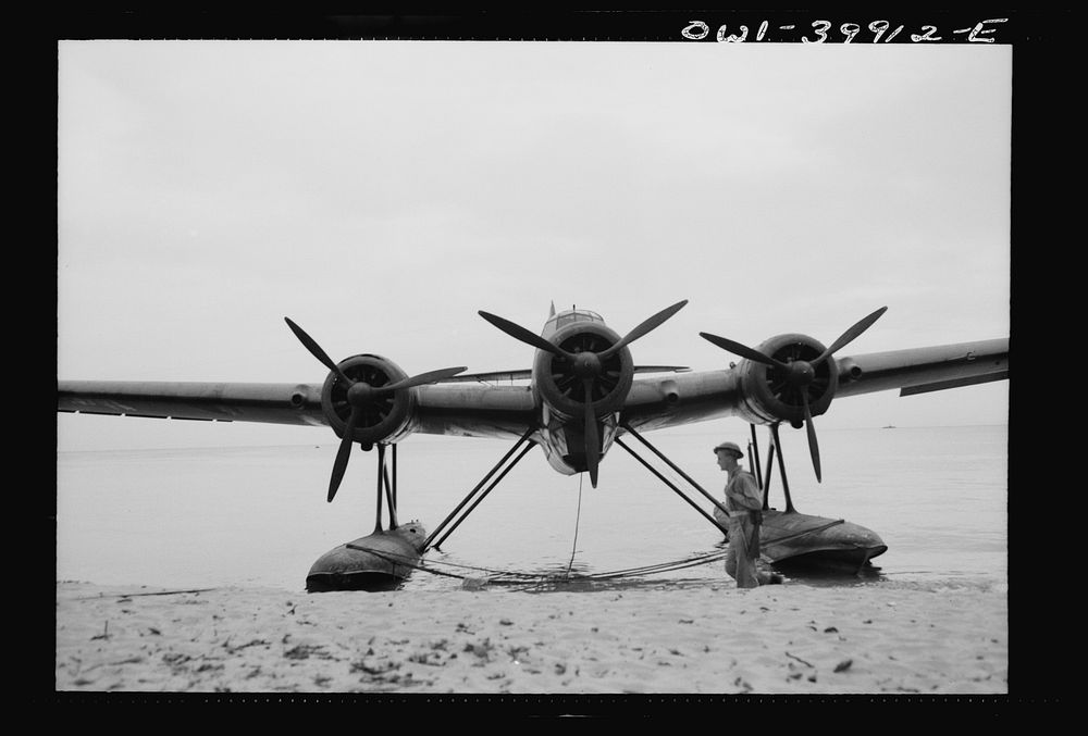 An Italian seaplane on a Sicilian beach guarded by a British soldier. Sourced from the Library of Congress.